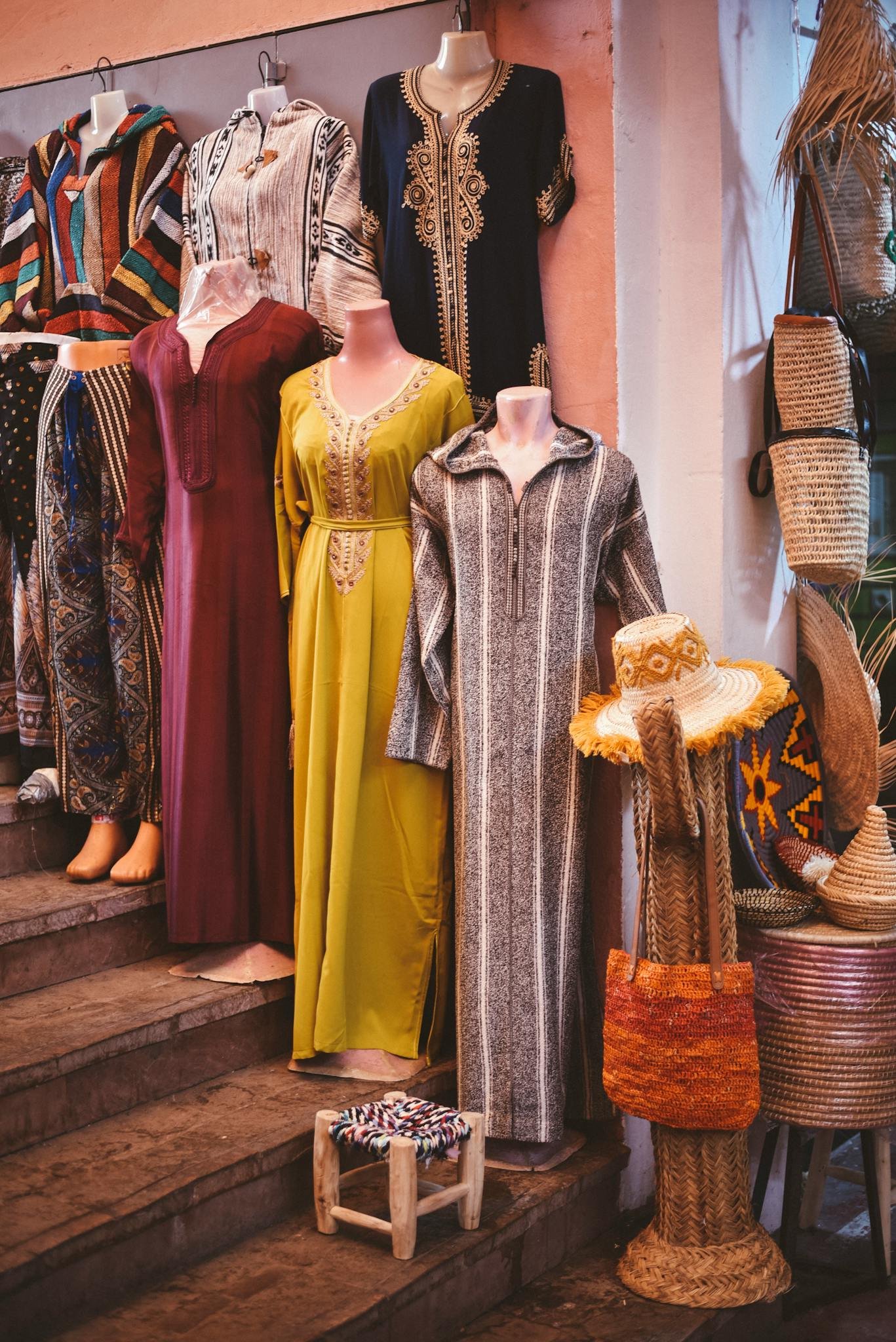 Vibrant display of traditional Moroccan dresses and artisanal crafts in an Agadir shop.