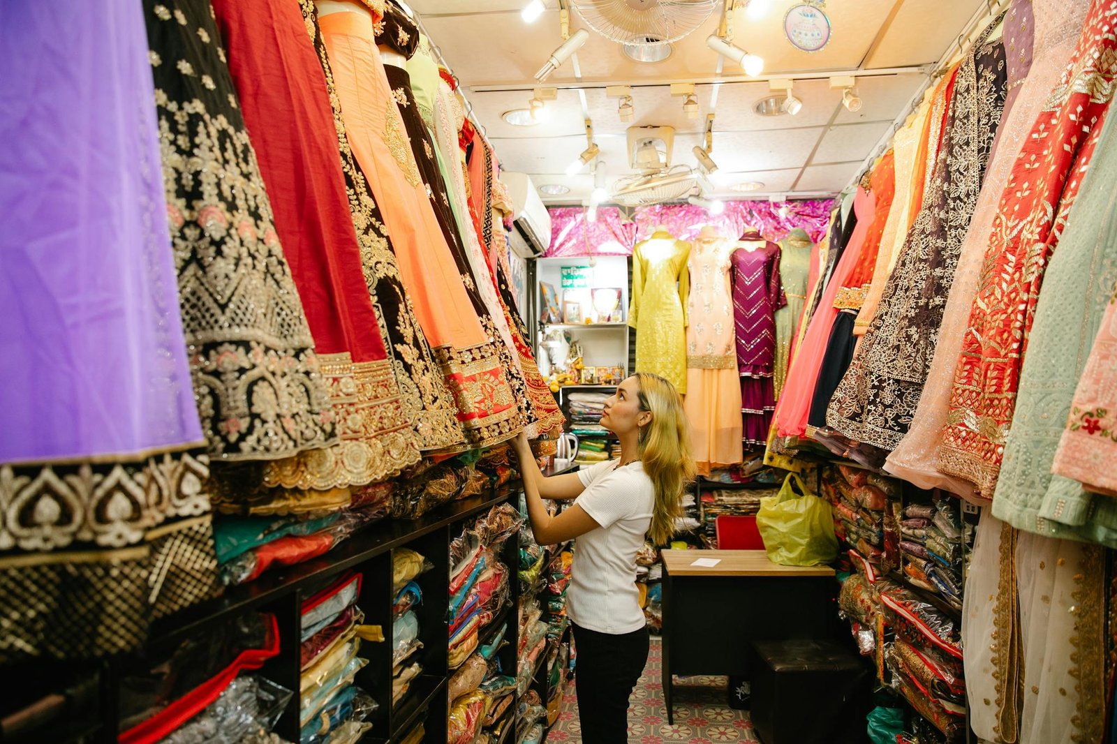 Woman exploring colorful traditional dresses in a boutique store.